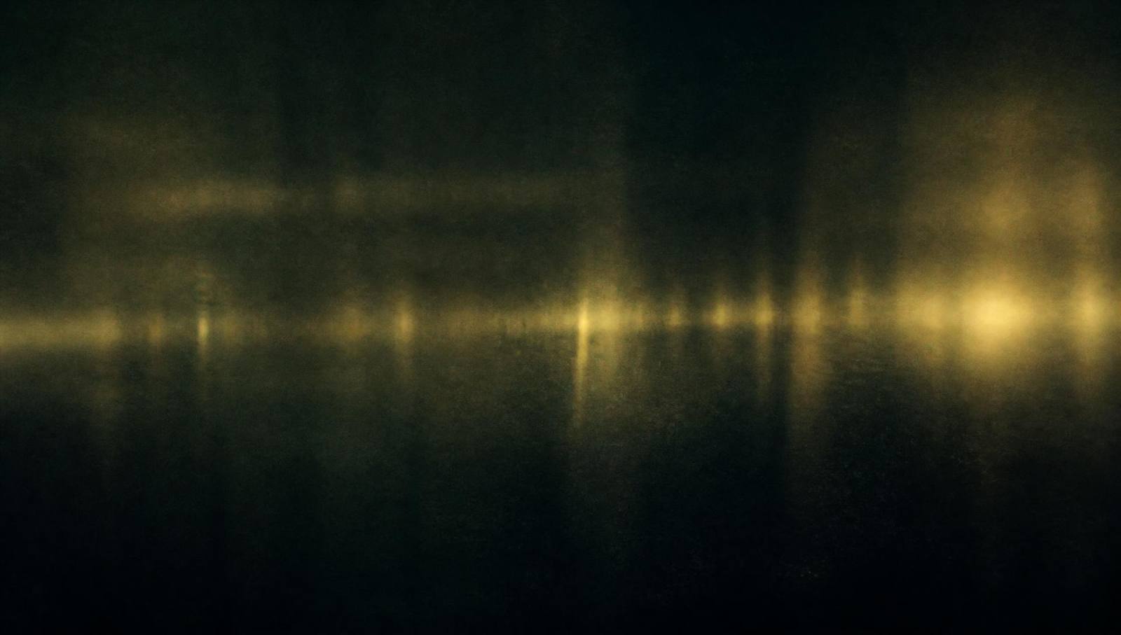 A dark room lit by a single warm lamp, dust in the light, a guitar leaning against a chair